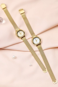 Macro detail of two gold mesh band watches on pink satin with pearl accents