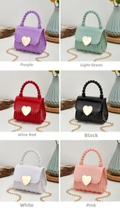 Détail de mini sacs en silicone en forme de cœur avec poignées torsadées et chaînes dorées