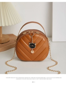 Close-up of V-quilted brown PU leather bag with black cat charm and gold chain strap