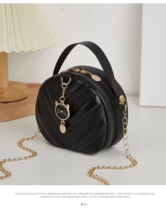 Detail of V-quilted black leather bag with a gold cat charm and metal chain strap