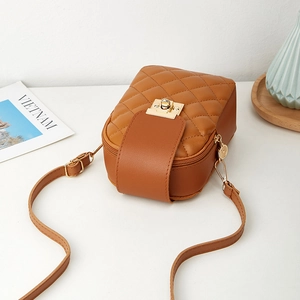 Caramel quilted crossbody bag with gold buckle on a white tabletop lifestyle setting