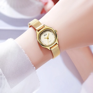 Close-up of golden mesh band quartz watch with rectangular textured dial on female wrist