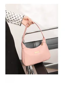 Detail of pink pebbled leather handbag featuring elegant gold metal hardware and charms
