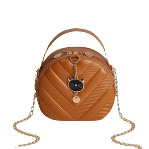 Quilted brown round crossbody bag with gold chain and black cat pendant accessory