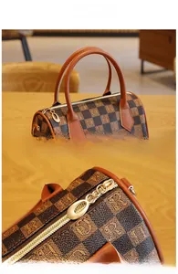 Close-up of reinforced leather handles and custom gold zipper on the plaid Boston bag