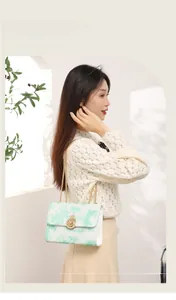 Detail of white and green marble texture crossbody bag with gold crown buckle and chain