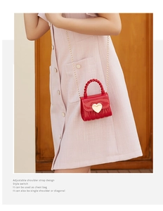 Red heart-shaped mini jelly bag with golden chain strap worn as a stylish crossbody bag