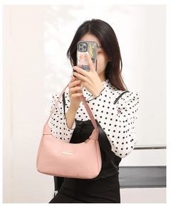 Detailed view of a stylish pink pebbled leather shoulder bag carried by a model