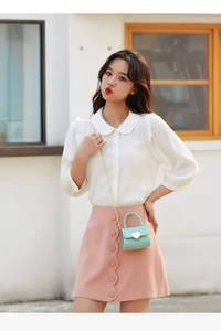 Detail of mint green silicone mini heart bag with chain strap on a white blouse