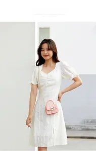 Mini pink jelly crossbody bag with heart lock and chain strap shown on white dress