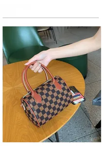 Close-up of a vintage brown checkered Boston bag with letter patterns on a wooden table