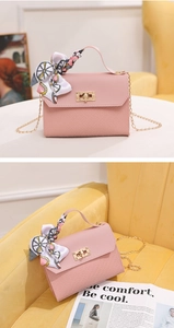 Detail of pink woven crossbody bag with gold twist lock and silk scarf handle decoration