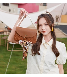 Detail of brown quilted crossbody bag featuring a pearl handle and vintage silk scarf