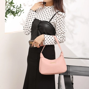 Pink pebbled leather shoulder bag for women with gold metallic plaque on a model
