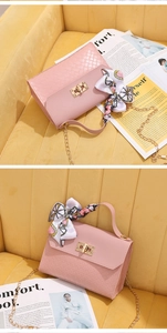 Close-up of pink woven bag with gold clasp and silk scarf handle on fashion magazine
