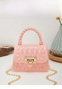 Pink jelly bag featuring pyramid studs, woven handle and gold chain in a bright setting