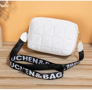 Détail d'un sac bandoulière blanc matelassé avec large sangle logo et boucles dorées