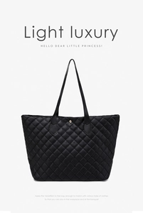 Macro detail of black quilted tote bag texture with a gold metal stud fastener