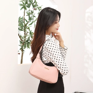 Elegant pink lychee leather hobo bag with gold metal logo bar worn on shoulder