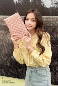 Détail de la pochette rose à matelassage avec fermoir rotatif doré et dragonne