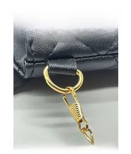 Close-up of quilted black leather texture and gold-plated D-ring buckle on small handbag