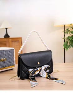 Detail of black quilted bag with pearl handle and decorative silk scarf on the flap