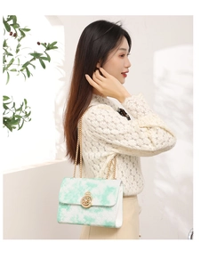 Detail of green cloud pattern quilted bag with golden crown buckle and chain strap