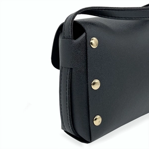 Side detail of black litchi grain leather bag with three golden round rivets