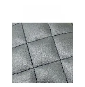 Detailed close-up of black quilted leather material with fine embroidery textures
