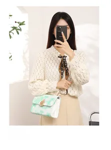 Model wearing a green cloud pattern crossbody bag with gold chain and circular clasp