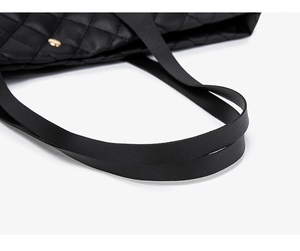 Detail view of black quilted tote bag with matte finish and gold metal hardware accents