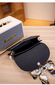 Close-up of black quilted bag with pearl handle, silk scarf and gold magnetic closure