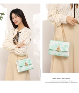 Detail of mint green embroidered crossbody bag with gold chain strap and metal buckle
