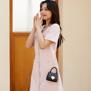 Mini sac bonbon en silicone noir avec boucle cœur dorée et bandoulière chaîne sur modèle