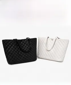 Detailed view of quilted tote bags in black and white with polished metal button accents