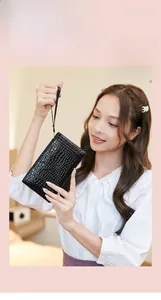 Detail of black crocodile texture clutch purse held by a woman in a lifestyle setting
