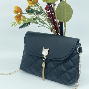 Close-up of black quilted shoulder bag with cat-head hardware and golden tassels