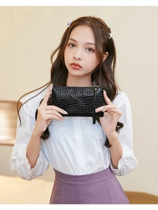 Detail of a black faux crocodile skin long wallet with a zip closure and a matching wristlet strap