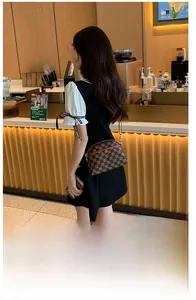 Sac bandoulière à carreaux marron porté par une femme dans un café à l'ambiance chaleureuse