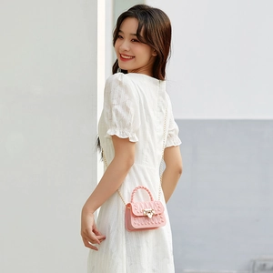 Mini sac en PVC rose avec rivets et bandoulière chaîne porté par un mannequin avec style