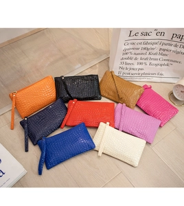 Various colors of crocodile pattern clutches with wristlets on wooden background