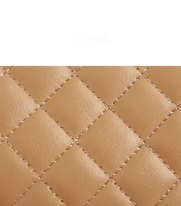 Close-up of light brown quilted fabric with detailed rhombus embroidery on handbag