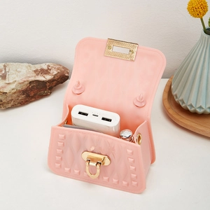 Pink mini silicone jelly bag with rivet texture and gold lock on a white table