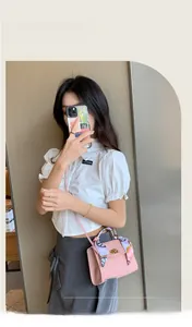 Rosa karierte Handtasche mit geprägtem Muster und dekorativem Seidenschal am Griff im Detail