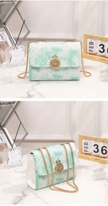 Close-up of mint green tweed chain bag with gold crown buckle on marble background