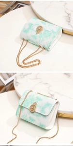 Detail of mint green tie-dye crossbody bag with gold chain strap and metal buckle