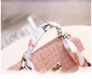 Detail der rosa gesteppten PU-Lederhandtasche mit Seidenschal-Wickel und goldener Schnalle