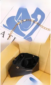 Detail of adjustable golden chain strap and interior of black quilted bucket bag