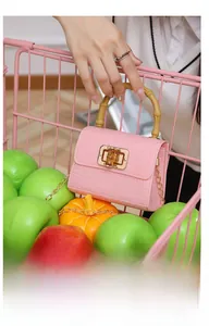 Vue détaillée d'un sac à main rose en gelée avec poignée en bambou et chaîne dorée