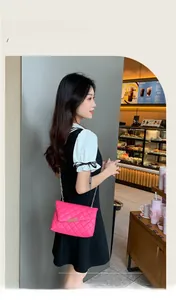 Detail of rose pink quilted crossbody bag with gold chain strap worn by a female model